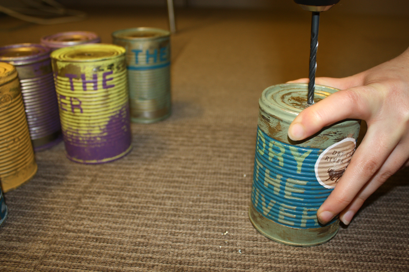 The tin cans being hand finished with the details of each song.