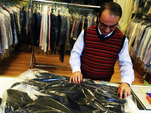 A member of staff at the dry cleaners hands over the dinner jacket to PopJustice.