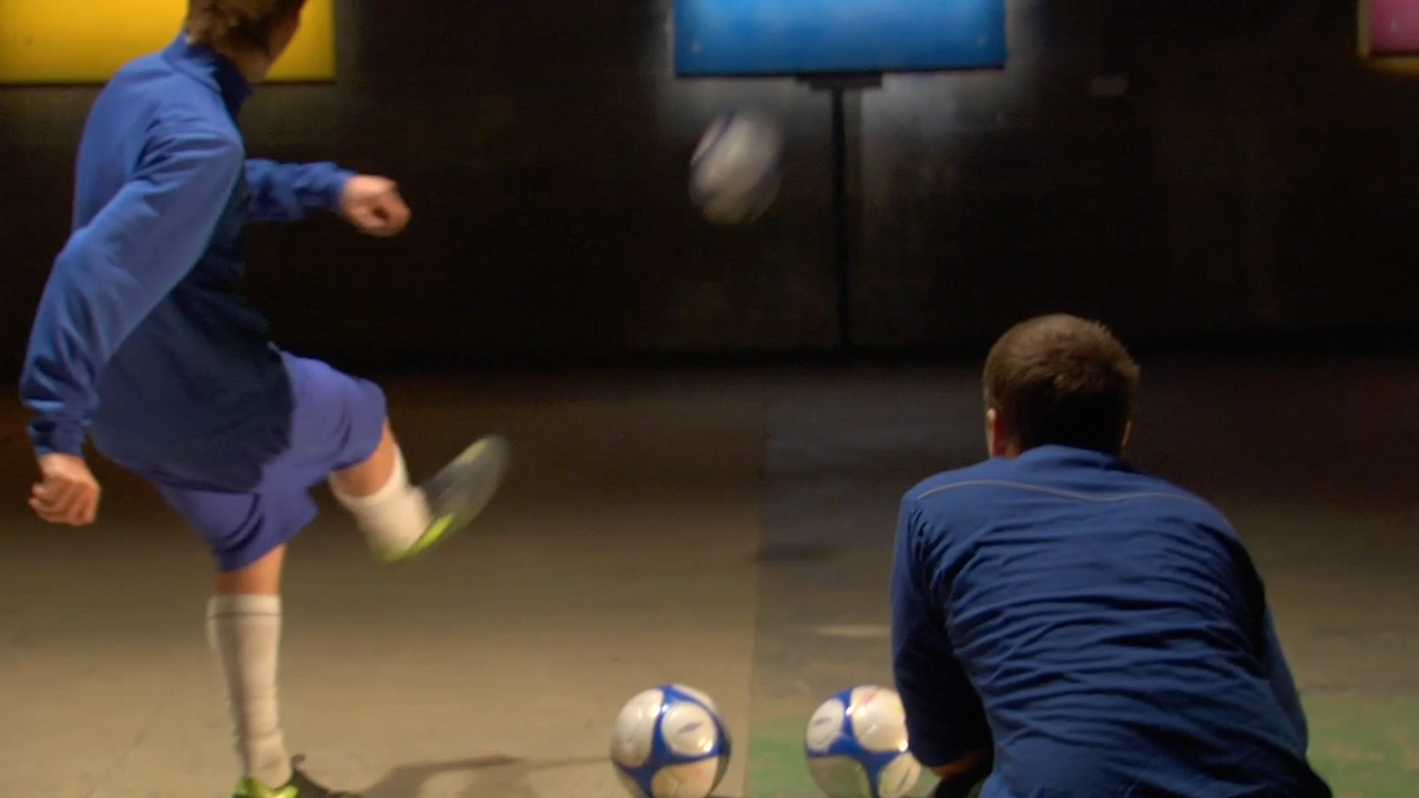 A close up of a footballer kicking the ball towards one of the control pads.